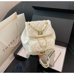 Detailed macro view of quilted cream leather texture with gold chain straps and metal turn locks