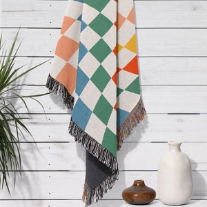 Close-up of geometric woven blanket with colorful diamond patterns and fringe details
