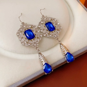 Close-up of vintage silver earrings with blue gemstones and rhinestones on beige velvet