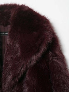 Dettaglio della texture in ecopelliccia bordeaux e del colletto a rever sul cappotto