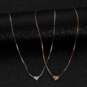 Close-up of minimalist heart pendant necklaces in gold and silver mirror finish metal