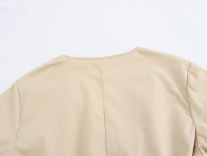 Détail du col en V de la robe beige avec une texture brodée de haute qualité
