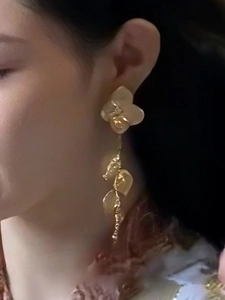 Gros plan détaillé de boucles d'oreilles feuilles en métal avec fleurs en résine blanche