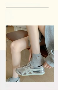 Close-up of grey polka dot cotton socks with cute dog embroidery paired with silver sneakers