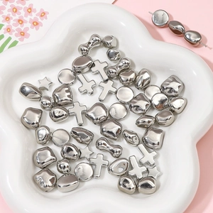 Various irregular silver beads including cross and star shapes in a ceramic dish