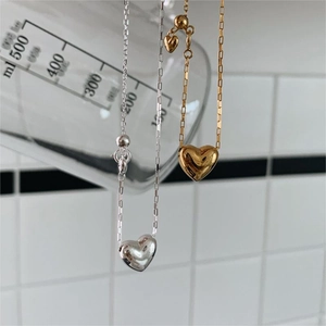 Macro shot of silver and gold heart pendants hanging on a glass beaker on white tile