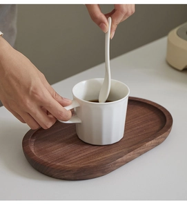 Close-up van een hand die koffie roert in een mok op een ovaal houten dienblad