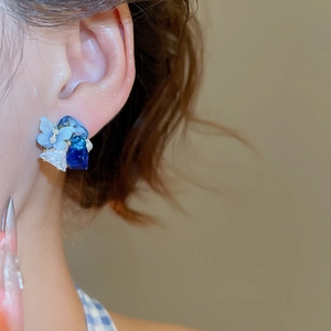 Close-up of blue crystal flower earrings with pearls and 18k gold plating details