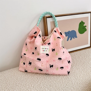 Detail of pink bubble texture tote bag with black cat print and woven green handles