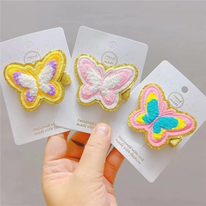 Close-up of three plush embroidered butterfly hair clips with sequins on cardboards