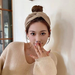 Detail view of a beige knotted headband on a model for a soft winter accessory style