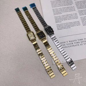 Three rectangular steel band quartz watches in gold and silver finishes on textured paper