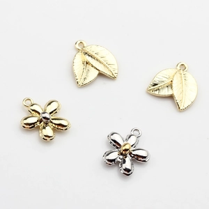 Detailed view of four mini metal leaf and flower charms for DIY jewelry making