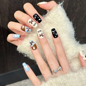 Winter themed handmade press-on nails with bow and snowflake designs on hands