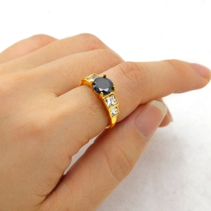 Detailed view of a gold ring featuring a round black gemstone and square zircon accents