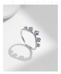 Detail of V-shaped crown ring with blue and pink gemstones on white background