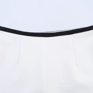 Close-up of the contrast waistband detail on the white shorts with black piping