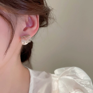 Macro detail of geometric multi-layered pavé diamond earrings with white pearl drop on model