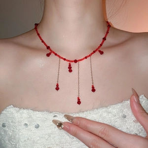 Detail of red crystal beaded necklace featuring three elegant gold tassel pendants on neck
