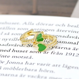 Macro shot of gold heart hoop earrings with green enamel and side zircon micro-inlay