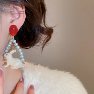Détail de boucles d'oreilles lapin avec perles et anneau bleu portées par un mannequin