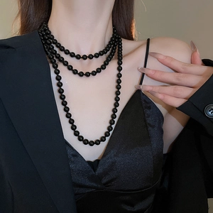 Detail shot of elegant three-layer long black bead necklace on a model wearing black suit