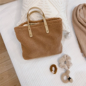 Detailed close-up of brown faux shearling tote bag with soft texture and leather handles