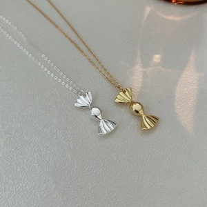 Dettaglio di collane con ciondoli a forma di caramella in argento e oro lucido