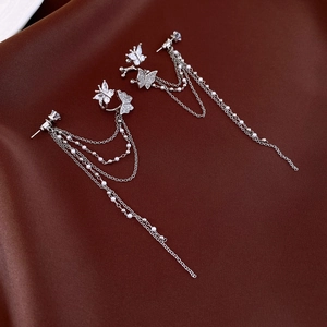Macro shot of silver butterfly tassel earrings with sparkling cubic zirconia on silk