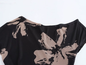 Gros plan sur le tissu en maille noire avec imprimé floral beige et épaule asymétrique
