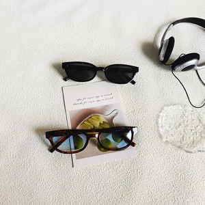 Close-up of black and tortoiseshell sunglasses with blue light lenses on a white surface
