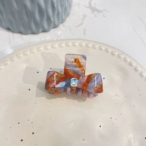 Bow-shaped marble pattern acetate hair claw clip with a sparkling rhinestone center