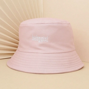 Dettaglio ravvicinato del cappello pescatore rosa con ricamo babygirl bianco su cotone