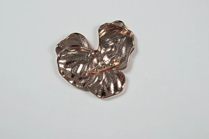 Détail du dos d'une broche feuille en or rose avec épingle et texture quadrillée