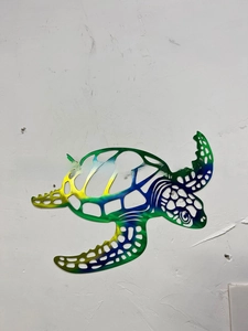 Detail of laser-cut hollow pattern on metal turtle wall art with colorful gradient finish
