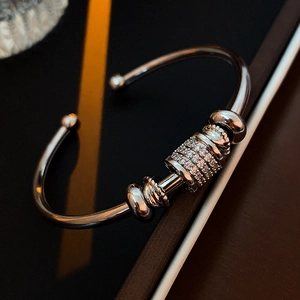 Macro detail of silver C-shaped cuff bracelet with pavé zircon cylinder and metal beads
