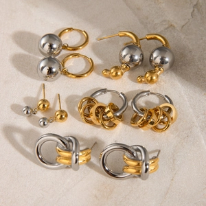 Mix of 18k gold and silver stainless steel earrings on a beige textured background