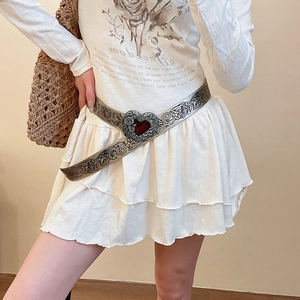 Detail of vintage leather belt with rose vine print and a red heart buckle on white skirt