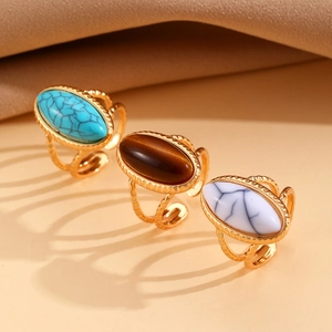Set de anillos dorados ajustables con ojo de tigre y turquesa sobre tela de seda