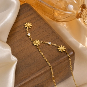 Detail of a golden flower Y-necklace with shiny zircon accents on a silk background