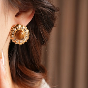 Dettaglio di orecchini vintage a fiore con occhio di tigre e diamanti sulla modella