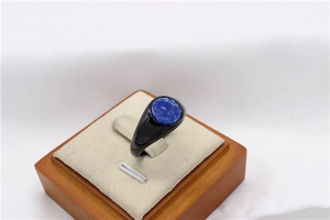 Close-up of a round blue lapis lazuli stone set on a polished black metal ring band