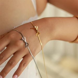 Elegant 18K gold and silver bow snake chain bracelets worn on a female wrist