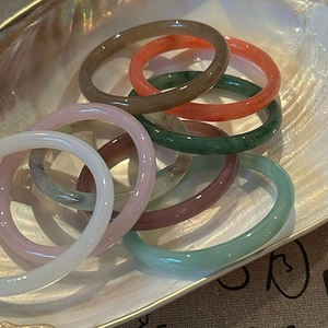 Stack of colorful translucent round bangles in a shell on a rustic linen background