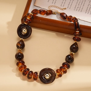 Detail of acrylic amber beads and golden rings on vintage book for women's necklace