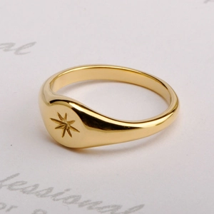 Detailed view of a gold signet ring with a starburst engraving and polished finish