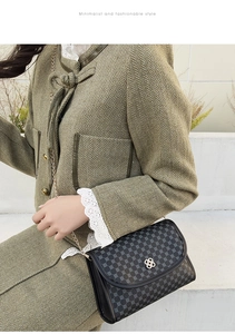 Minimalist chain crossbody bag with floral buckle shown on a green wool coat
