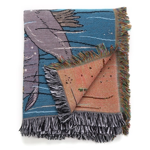 Close-up of woven whale pattern camping blanket with colorful decorative tassels