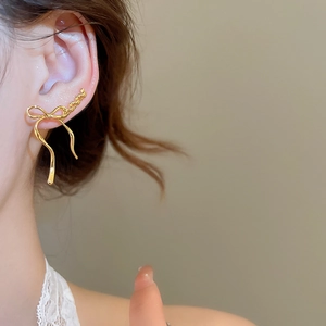 Close-up of elegant gold bow-shaped ear hook earrings with polished metallic finish