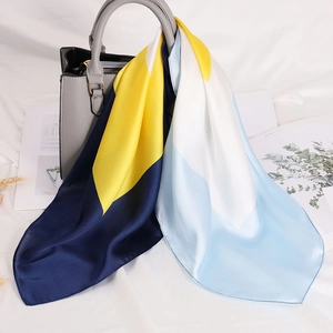 Foulard di seta a blocchi di colore blu e giallo annodato a una borsa grigia